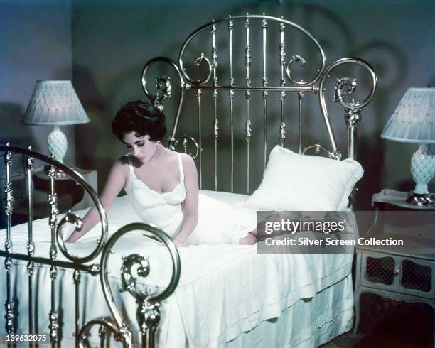 Elizabeth Taylor , British actress, wearing a white nightgown and sitting on a bed in a publicity still issued for the film, 'Cat on a Hot Tin Roof',...