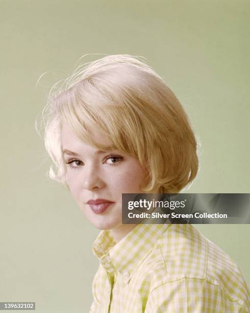 Headshot of Joey Heatherton, US actress, dancer, and singer, wearing a yellow and white check blouse in a studio portrait, against a yellow...
