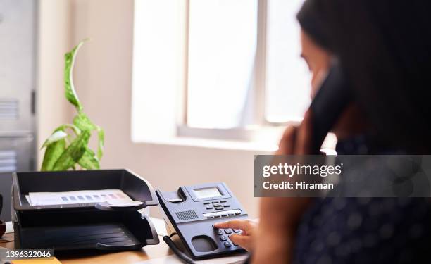 primer plano de una mujer haciendo una llamada por teléfono en una oficina sola. una mujer solo marca un número de teléfono con los dedos en un teclado en la recepción de una recepcionista. administrador y secretaria consultando y transfiriendo llamada - teléfono con cable fotografías e imágenes de stock
