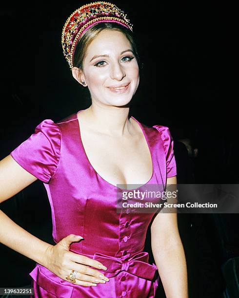 Barbra Streisand, US actress and singer, wearing a fuchsia pink silk dress with a scoop neckline and a matching bow around the waist, circa 1965.