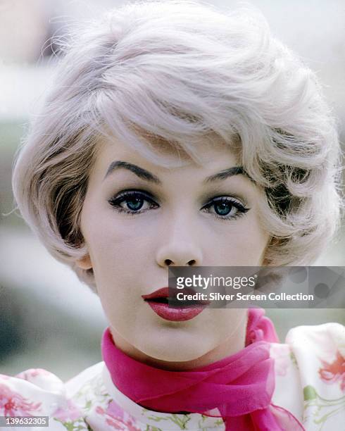 Headshot of Stella Stevens, US actress, wearing a floral pattern blouse with a fuchsia pink neck scarf, circa 1960.