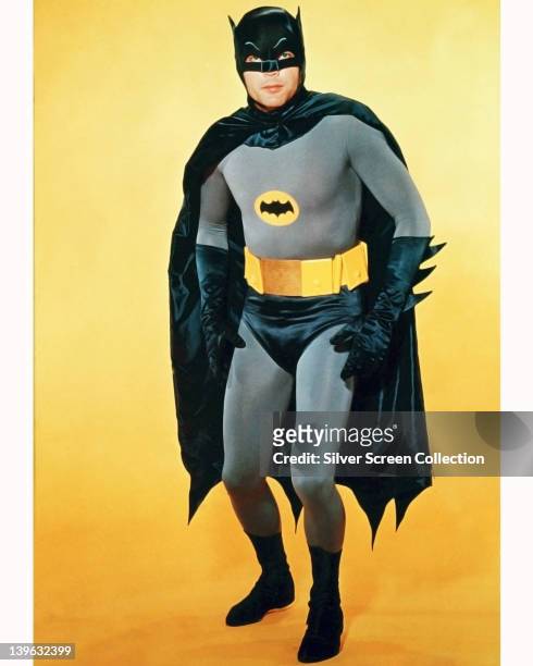 Adam West, US actor, in costume in a studio portrait, against a yellow background, issued as publicity for the television series, 'Batman', USA,...