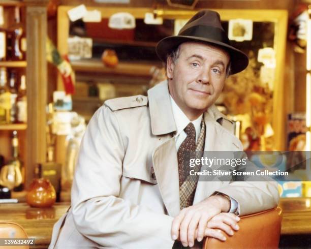 Tim Conway, US actor and comedian, wearing a beige overcoat over a tweed jacket, a white shirt and brown tie, with a brown fedora with a black band,...