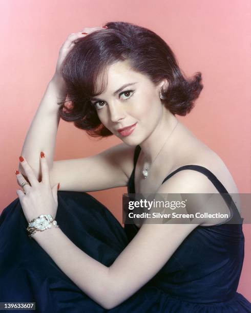 Natalie Wood , US actress, wearing a dark blue dress in a studio portrait, against a pink background, circa 1965.