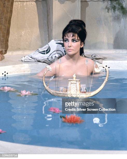 Elizabeth Taylor , British actress, bathing with a small boat and flowers floating on the water in a publicity still issued for the film,...
