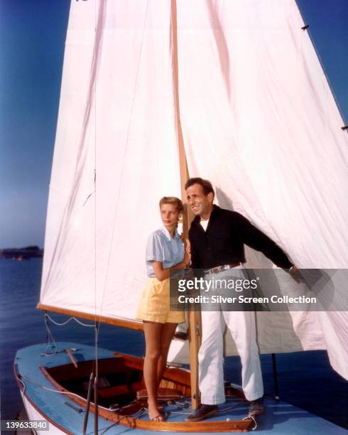 Lauren Bacall, US actress, and her husband, Humphrey Bogart , US actor, support themselves by holding the mast on a small sailboat, circa 1950.