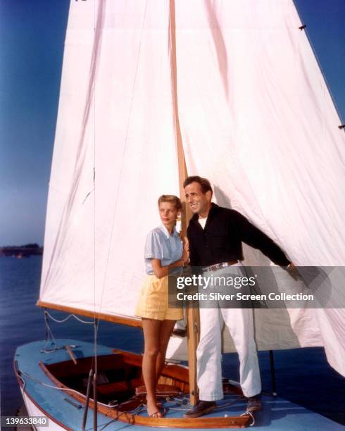 Lauren Bacall, US actress, and her husband, Humphrey Bogart , US actor, support themselves by holding the mast on a small sailboat, circa 1950.