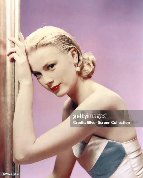 Grace Kelly , US actress, wearing an off-the-shoulder dress in a studio portrait, against a lilac background, circa 1955.