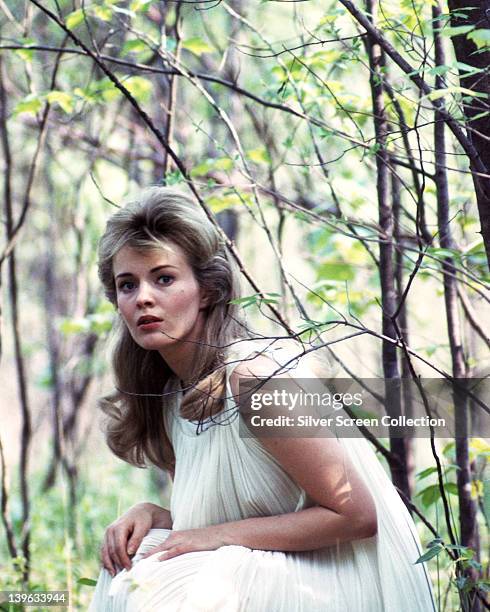 Jean Seberg , US actress, wearing a white dress as she sits among trees and foliage, circa 1970.