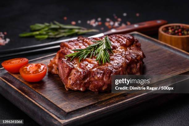 grilled ribeye beef steak,herbs and spices on a dark table - carne foto e immagini stock