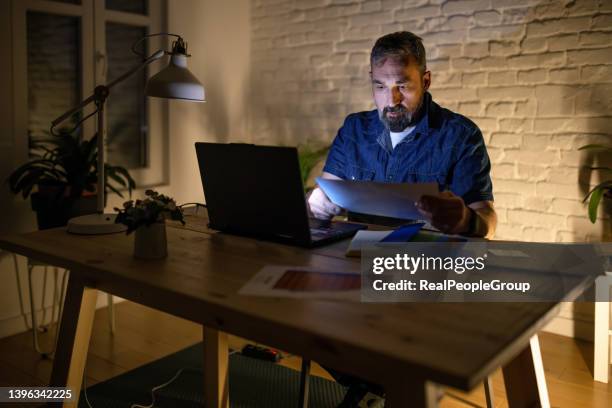 mature man in casual suit sitting at the table in home office and working at laptop - ekonomisk rapport bildbanksfoton och bilder