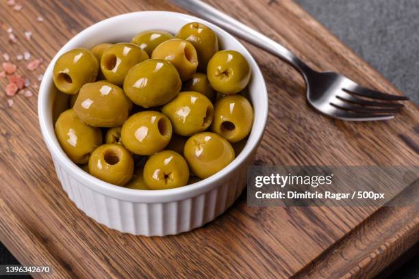 beautiful pickled green olives on a dark concrete background - green olive fotografías e imágenes de stock