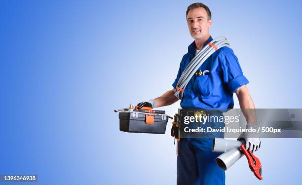 portrait of uniformed plumber with tools and blue isolated background - drain inspection stock-fotos und bilder