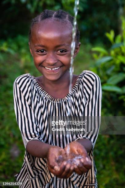 afrikanisches mädchen, das frisches wasser trinkt, ostafrika - african girl drinking water stock-fotos und bilder