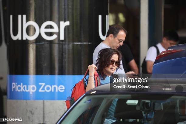 Travelers wait for an Uber ride at Midway International Airport on May 09, 2022 in Chicago, Illinois. Uber plans to cut spending and hiring in an...
