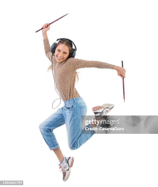 garota adolescente animada pulando e tocando bateria de ar com baquetas e fones de ouvido - baqueta instrumento musical - fotografias e filmes do acervo