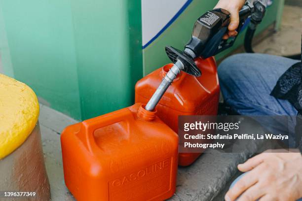 man filling up gas cans at gas station - benzinekan stockfoto's en -beelden