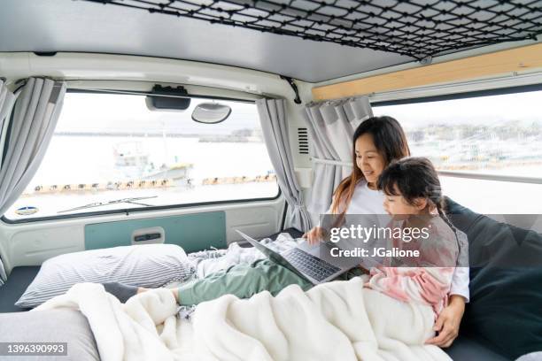 mother and daughter watching a laptop whilst relaxing in a camper van - wonderlust computer stock pictures, royalty-free photos & images