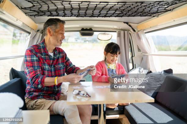 Grandfather playing cards with his granddaughter in a camper van