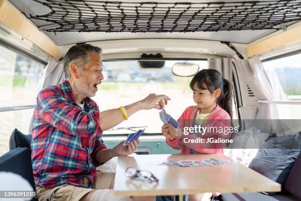 grandfather playing cards with his granddaughter in a camper van - camping games stockfoto's en -beelden