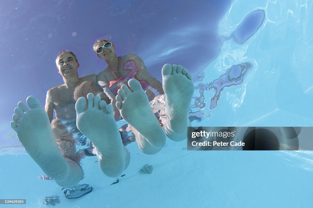 Couple sat at pool, view from underwater