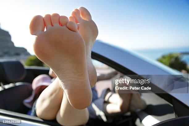 couple with feet up, relaxing in car by sea - female soles stock-fotos und bilder