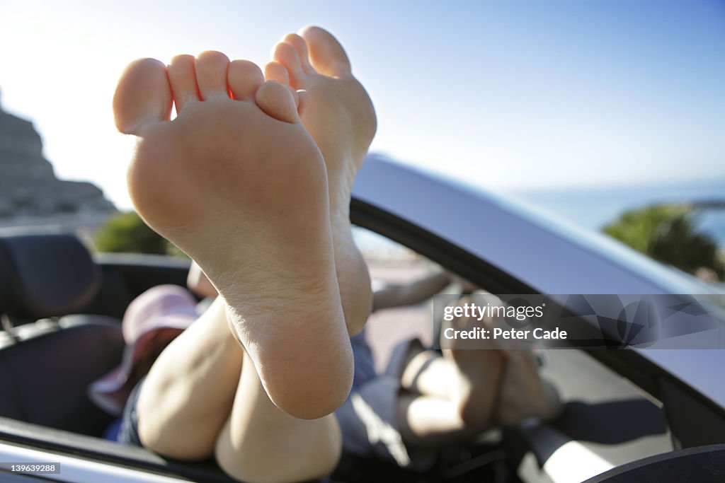 Couple with feet up, relaxing in car by sea