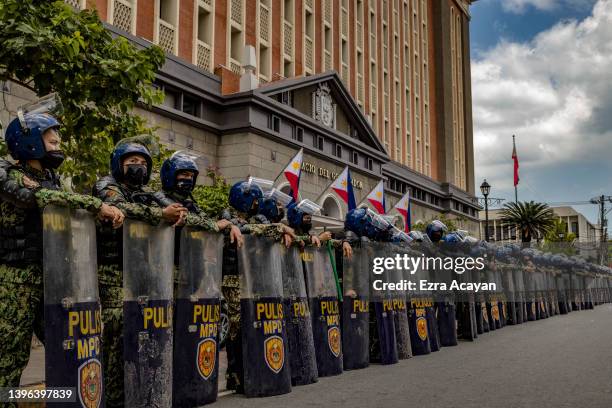 Police officers stand guard as Filipinos take part in a protest against election results outside the Commission on Elections building on May 10, 2022...