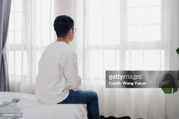 rear view of a man sitting by the window - single life stock pictures, royalty-free photos & images