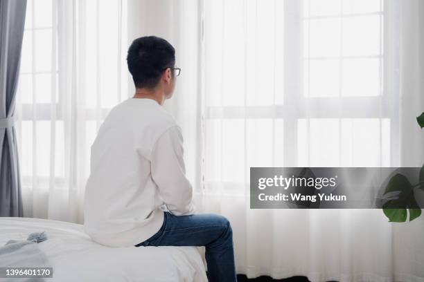 rear view of a man sitting by the window - the bachelor 個照片及圖片檔