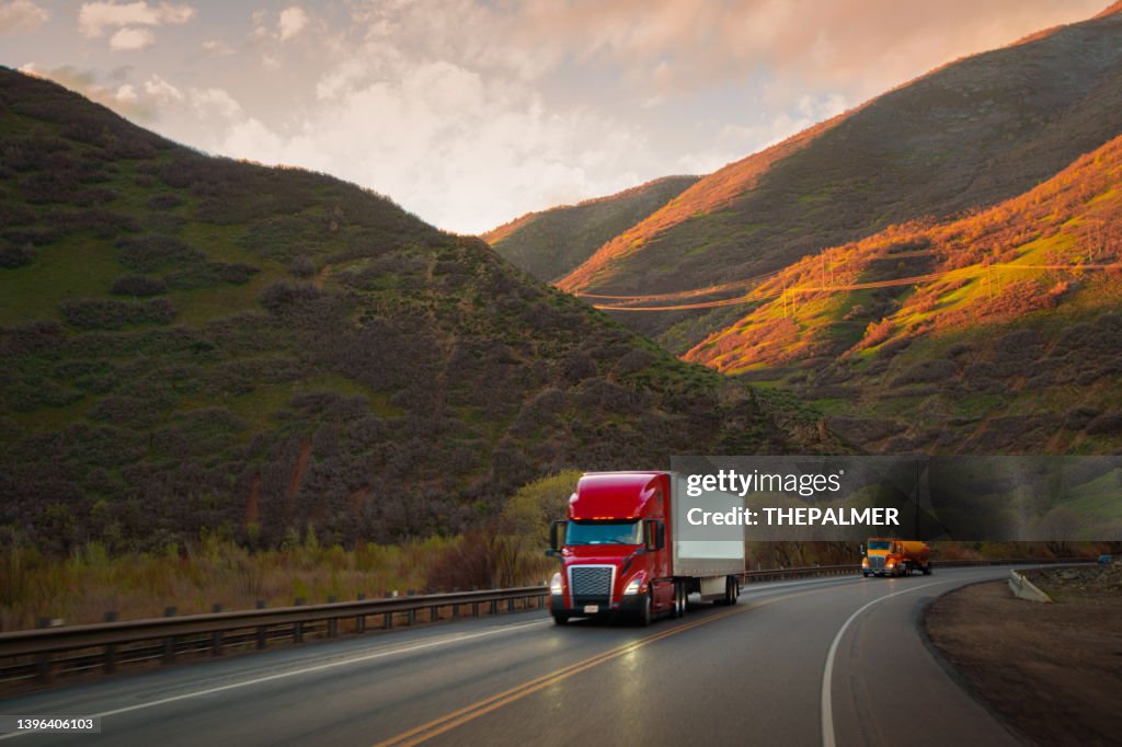 Red and white semi-truck driving in Utah mountain range