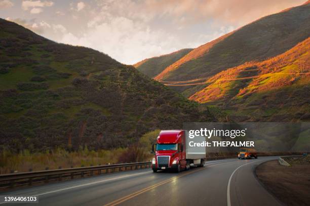 red and white semi-truck driving in utah mountain range - articulated lorry stock pictures, royalty-free photos & images