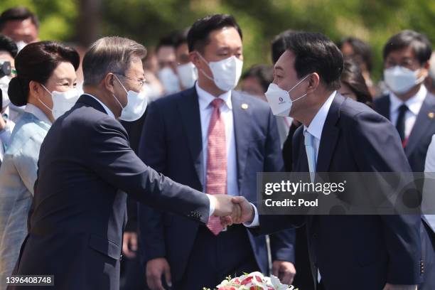 South Korea's new President Yoon Suk-yeol shakes hands with former President Moon Jae-in upon his arrival to his inauguration ceremony at the...