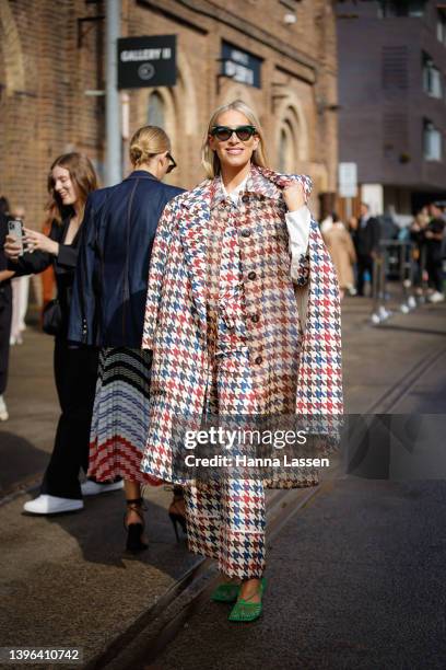 Phoebe Burgess is seen wearing Lee Matthews jacket and pants and green Bottega Veneta clutch and shoes at Afterpay Australian Fashion Week 2022 on...