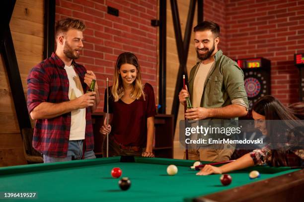 gruppe von freunden, die spaß beim billardspielen in einer örtlichen poolhalle haben - billard cue stock-fotos und bilder