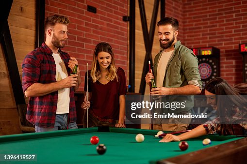 Group of friends having fun while playing pool in a local pool hall Group of friends having fun while playing pool in a local pool hall