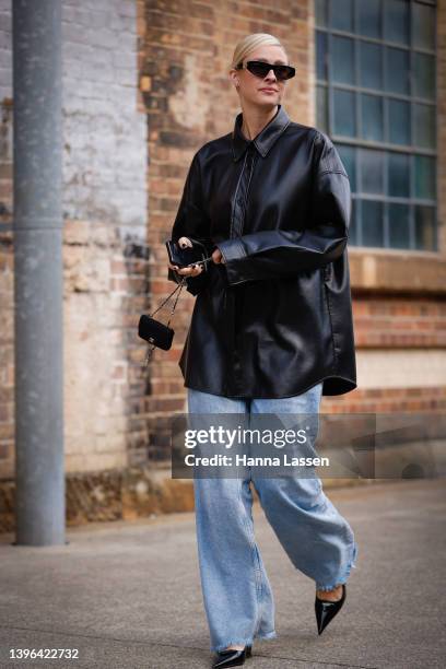 Guest wearing black leather shirt and jeans at Afterpay Australian Fashion Week 2022 on May 10, 2022 in Sydney, Australia.