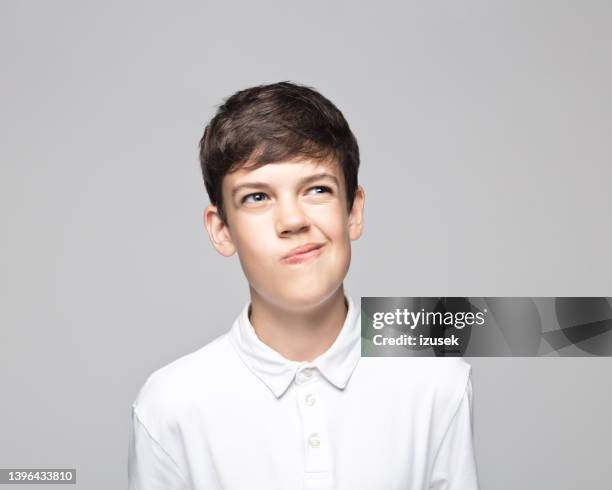 confused teenage boy against gray background - grimacing stock pictures, royalty-free photos & images