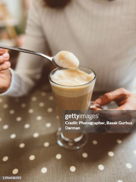 a woman drinking latte at a cafe, showing the milk froth on the spoon - coffee foam imagens e fotografias de stock