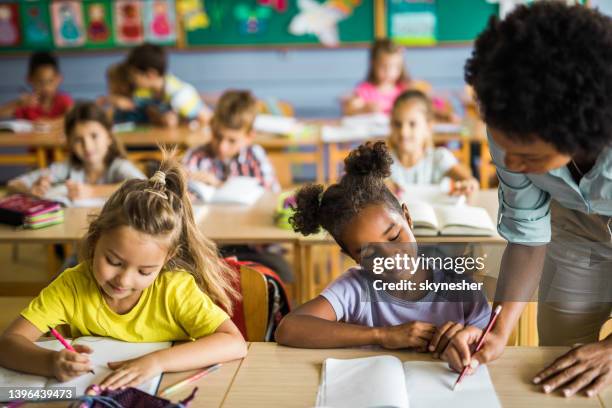 professeur noir aider les élèves du primaire sur une classe. - enseignante photos et images de collection