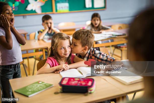 l’écolier mignon embrassant son premier amour dans la salle de classe. - young boy and girl in love photos et images de collection