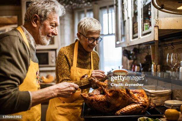 glückliches seniorenpaar schmücken truthahn am thanksgiving-tag. - chicken decoration stock-fotos und bilder