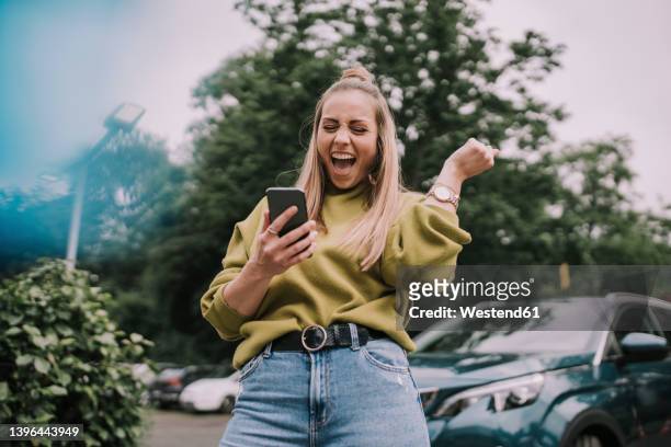 excited young woman using smart phone - entusiasmo fotografías e imágenes de stock