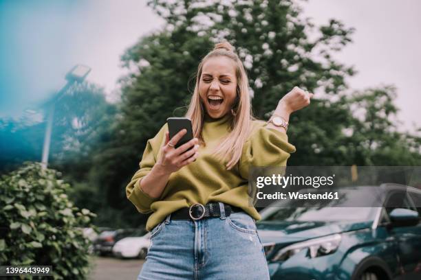 excited young woman using smart phone - car excitement stock pictures, royalty-free photos & images