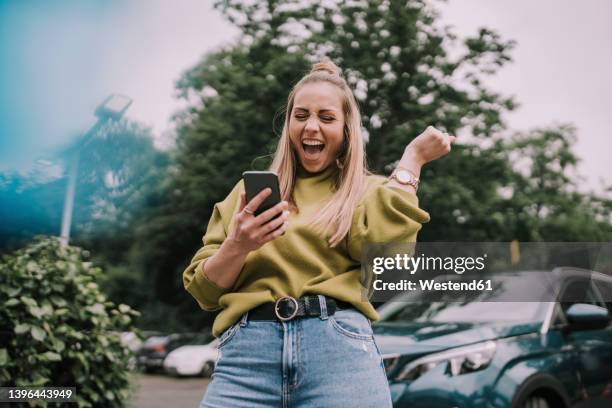 excited young woman using smart phone - smartphone car stock pictures, royalty-free photos & images