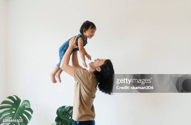 positive emotion happiness together asian mother holding daughter playing lift up at home domestic life. - boxen sport stockfoto's en -beelden