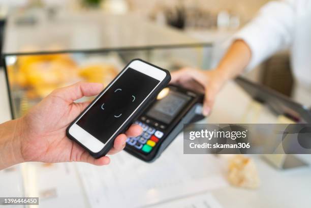 selective focus hand using phone scanning qr code for paying in the cafe from credit card reading. - brand name mobile payment stock-fotos und bilder