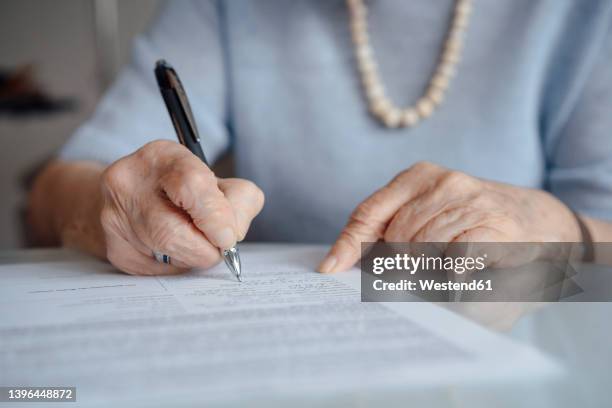 hands of senior woman writing on paper with pen - erfenis stockfoto's en -beelden