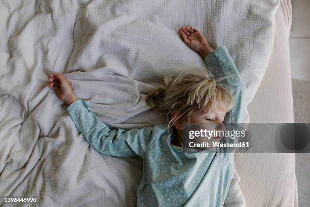 girl with blond hair sleeping on bed at home - kids sleep in bed stock-fotos und bilder