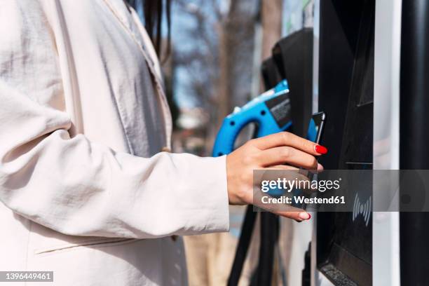 woman making contactless payment through smart phone at charging station - mobile payment stock pictures, royalty-free photos & images